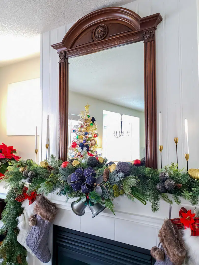 Christmas mantel with garlands, ornaments and candles.
