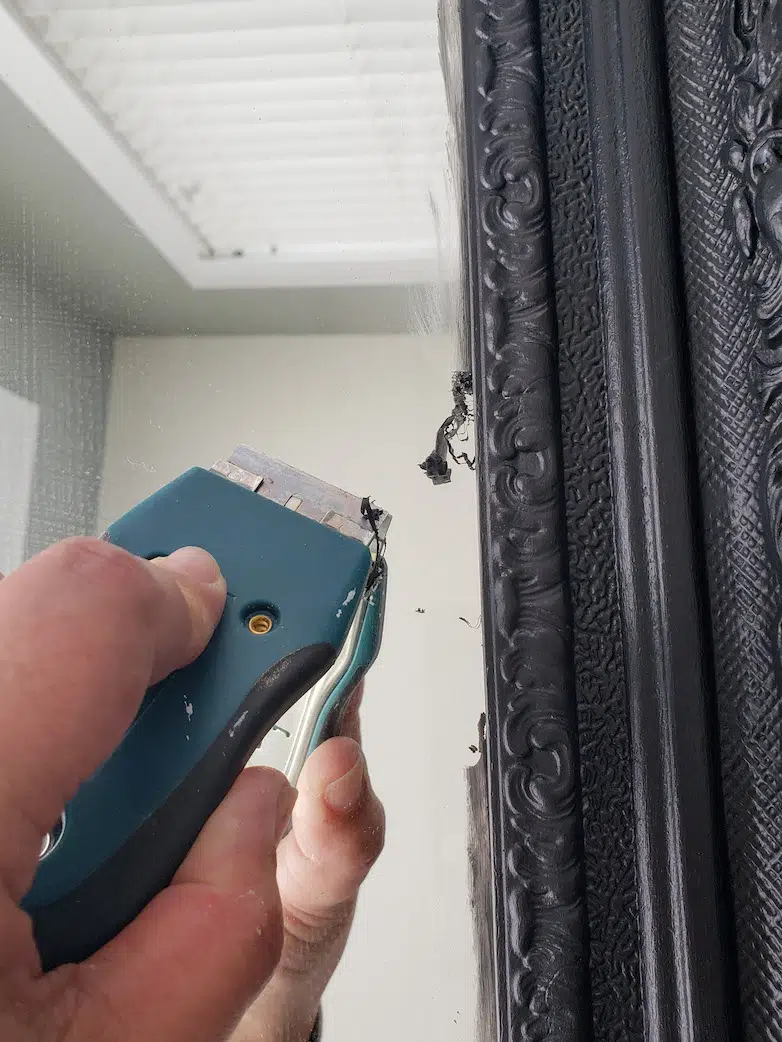 Scraping excess paint off a mirror