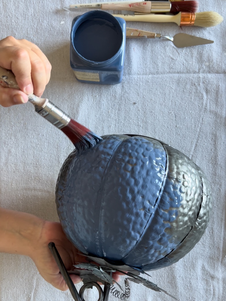 Decorating a pumpkin with blue paint
