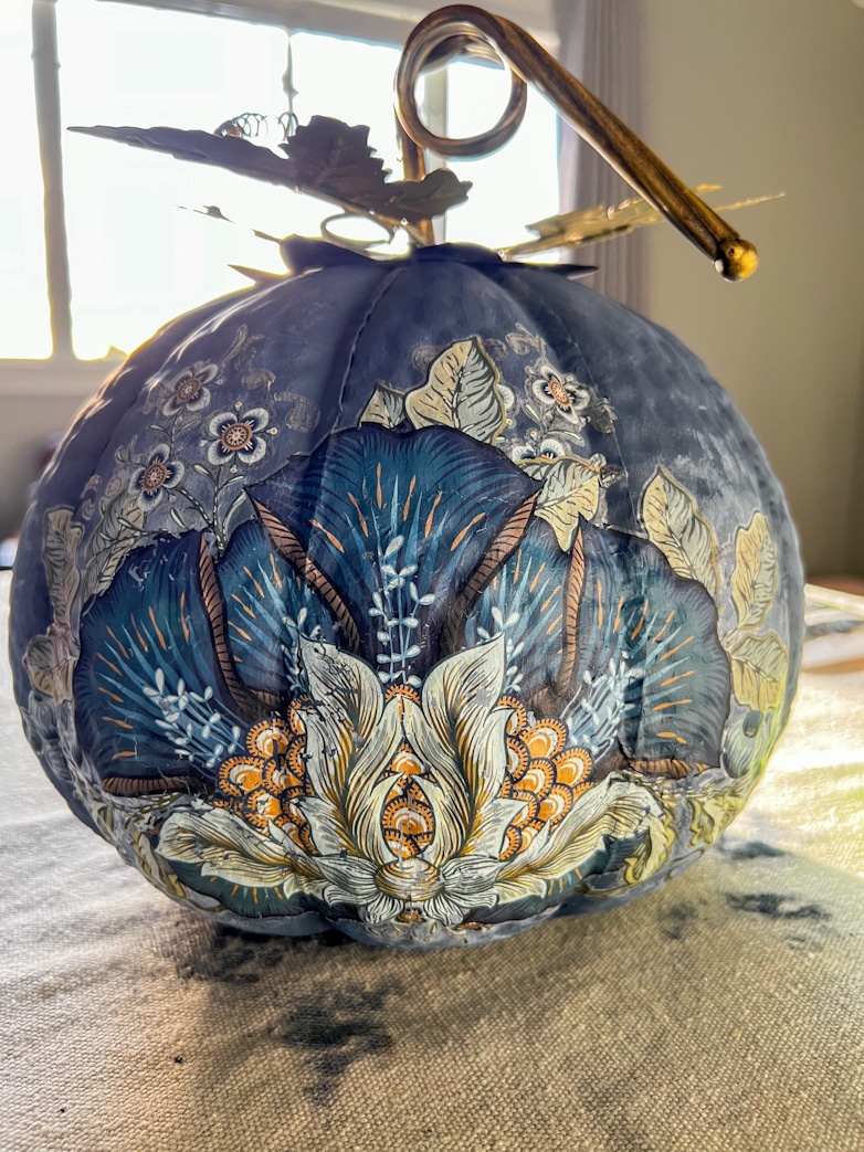 A blue painted pumpkin decorated with floral transfers