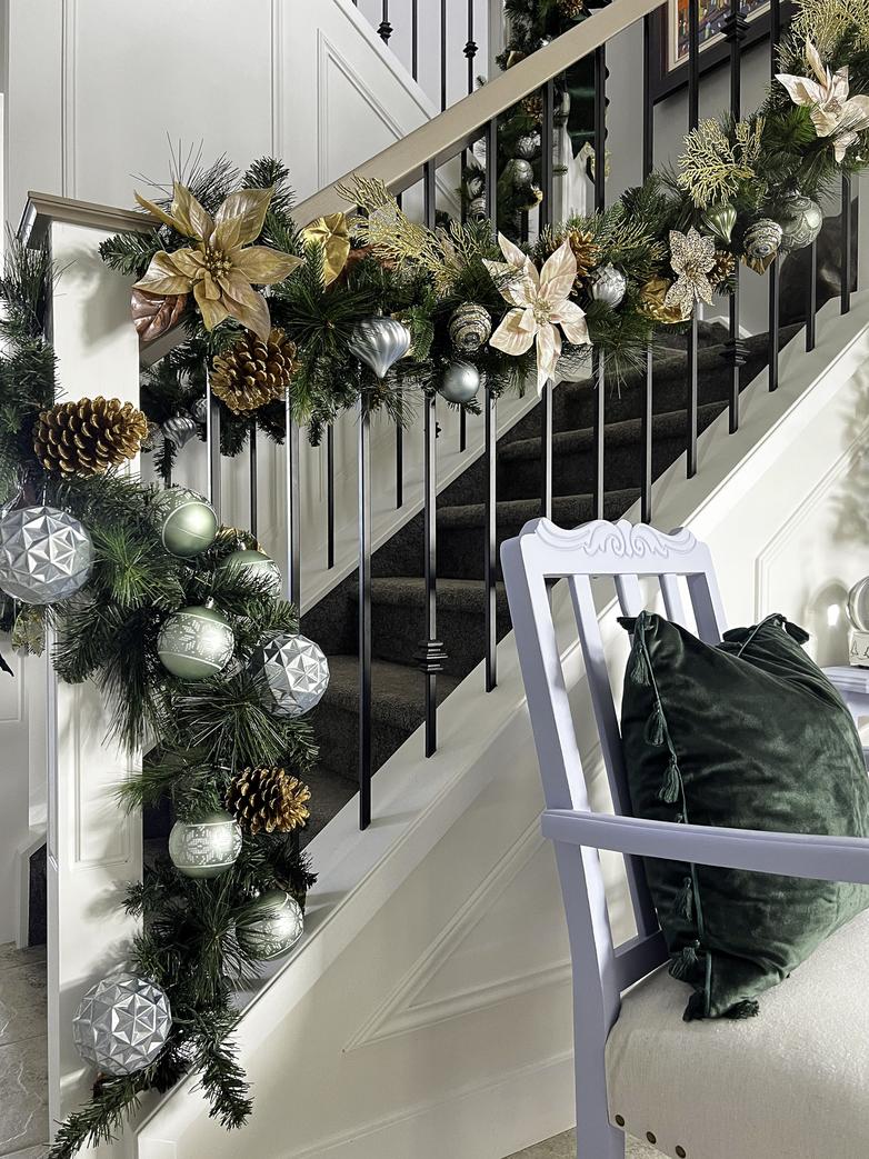 The entryway is decorated for Christmas with garland and metallic ornaments