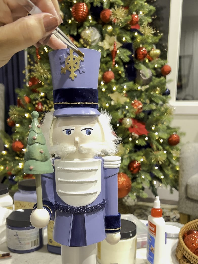 Painting small detail on the nutcracker with golden gilding wax