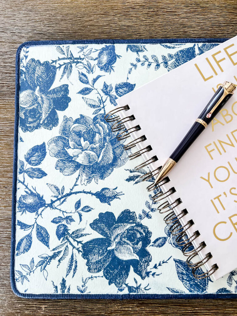 A deskpad decoupaged with rice paper with blue and white sketched flowers