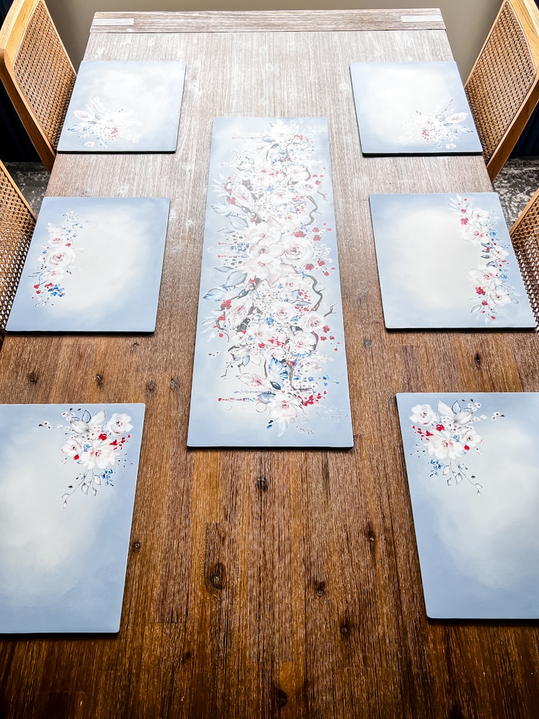 Six DIY placemats and a center piece made with hardboard, paint and transfer images