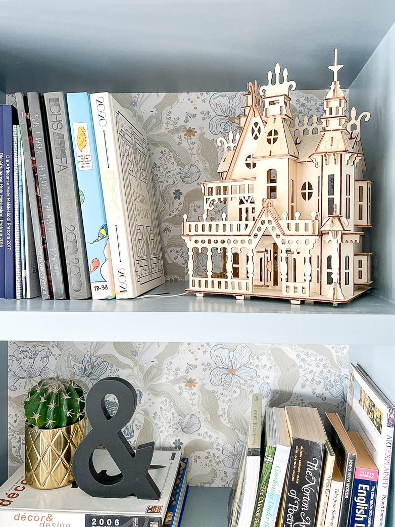 A 3D puzzle of a Victorian villa displayed on a bookshelf