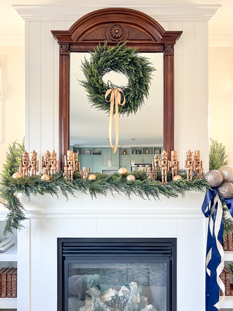 A mantel decorated for Christmas with gold nutcrackers and green garlands
