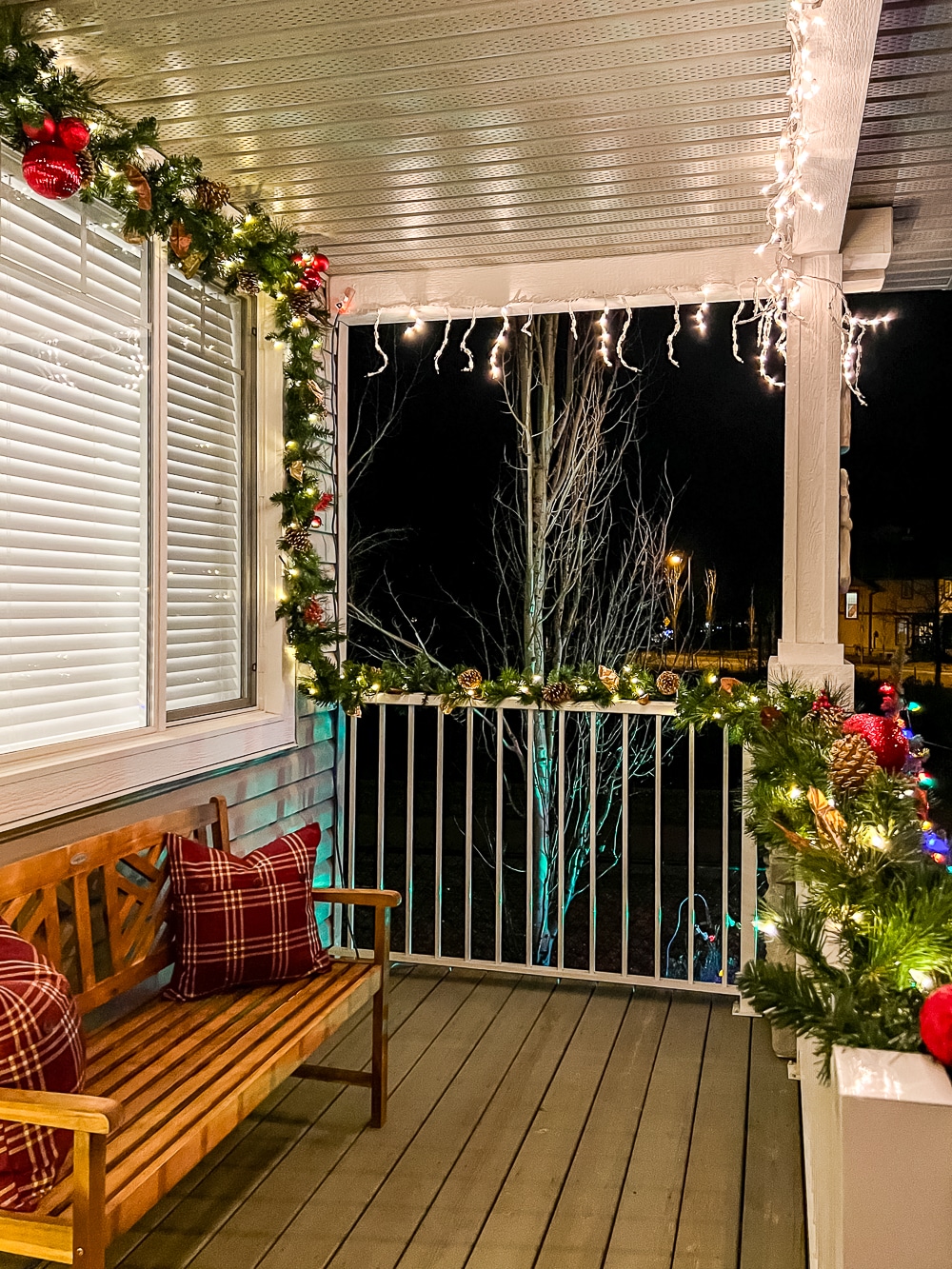 A cozy looking porch decorated for Christmas at night