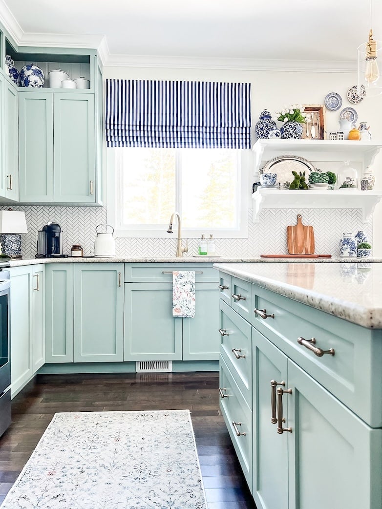 A kitchen with blue cabinets and white shelves