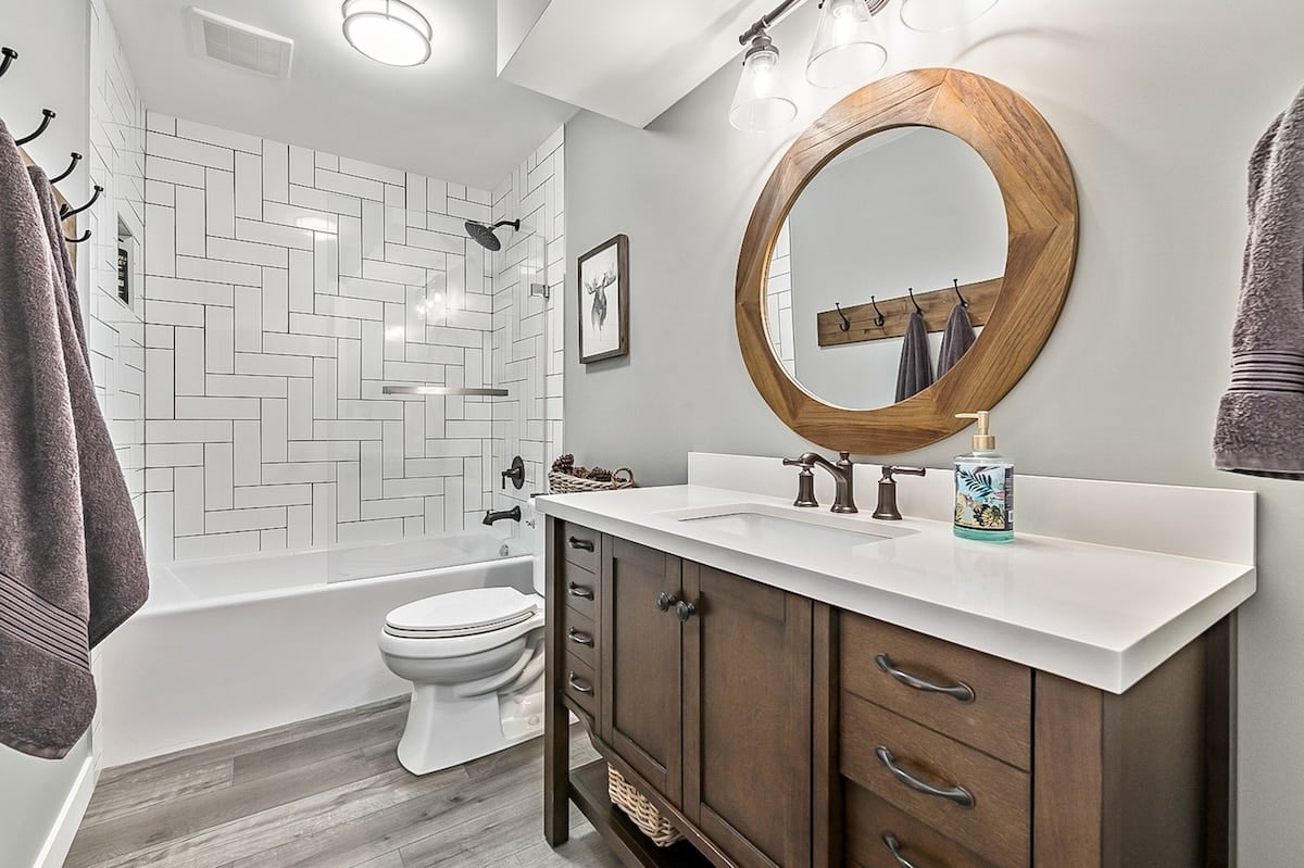 A bathroom with a round mirror and a tub