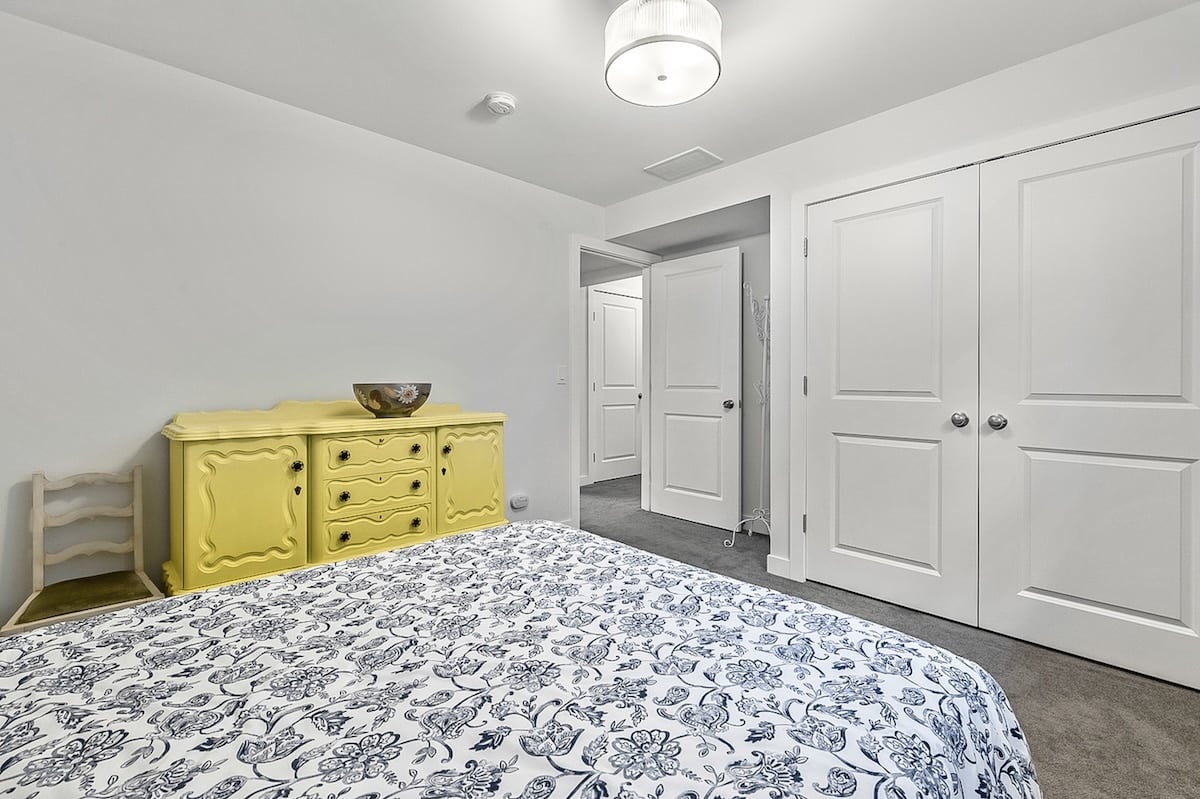 A bedroom with a yellow dresser and a bed